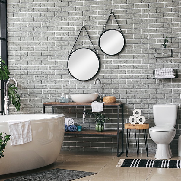 A clean bathroom featuring a white bath, toilet, and two wall-mounted mirrors.