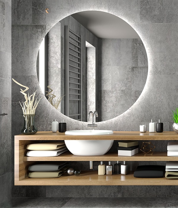 A modern bathroom featuring a round mirror above a sleek sink, showcasing contemporary design elements and neutral colours.